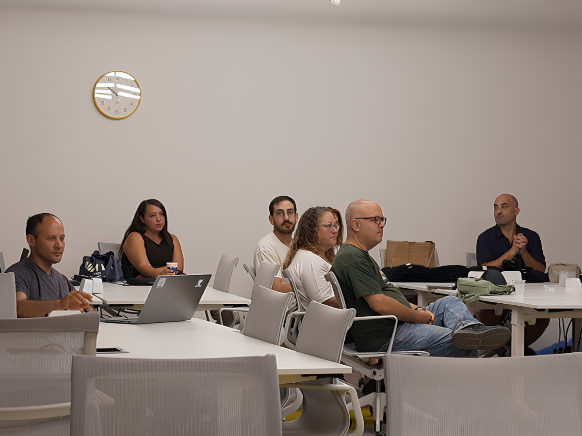 משתתפים יושבים סביב שולחנות עבודה באירוע יזמות